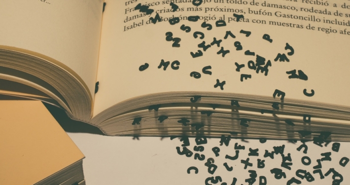 On open book with black text letters falling out of the pages.