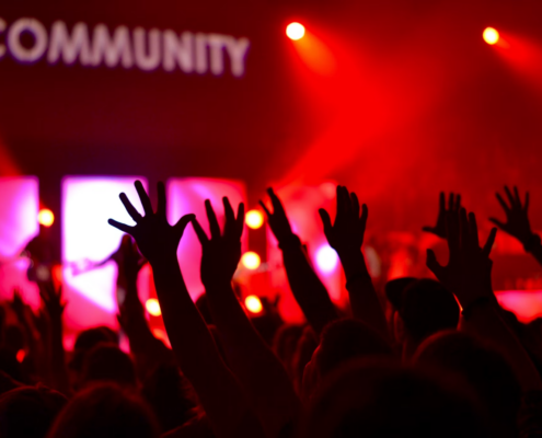 A music concert in hands reaching to the sky towards the word community