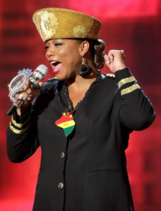 Hip-hop artist Queen Latifah singing into a microphone.