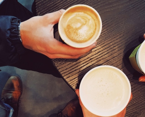 three people sitting around a table drinking coffee.