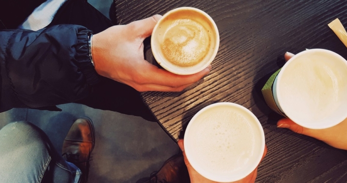 three people sitting around a table drinking coffee.