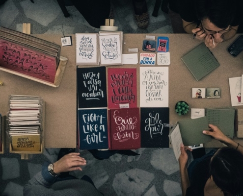 upper view of a table filled with home-made books and surrounded by people making them and looking at them