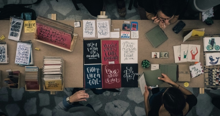 upper view of a table filled with home-made books and surrounded by people making them and looking at them