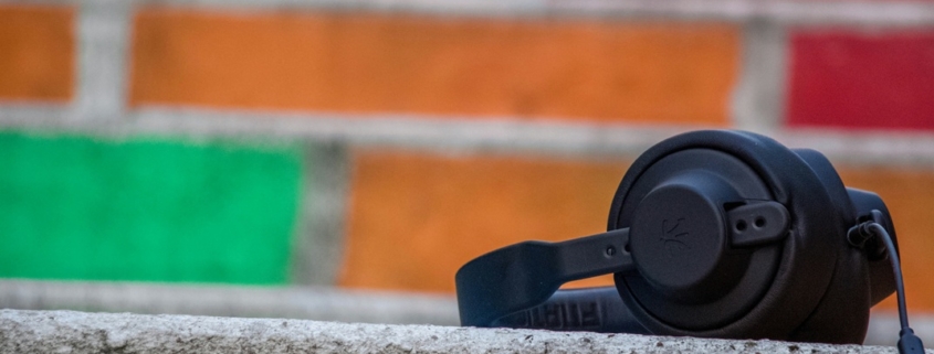 black headphones on a cement ledge in front of a wall of multi-coloured